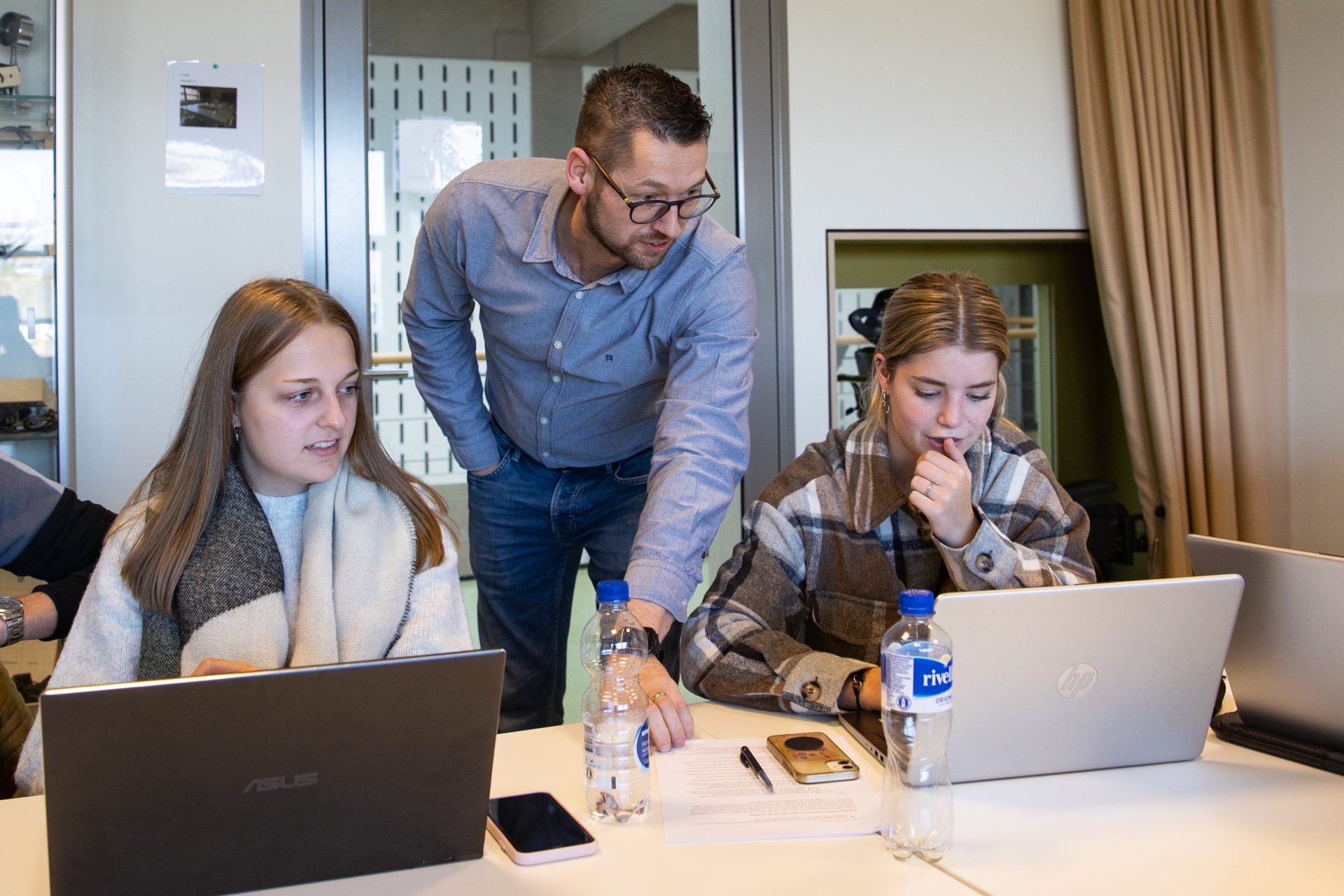 Een docent begeleidt twee leerlingen achter hun notebook bij onze leerlijn Readiness